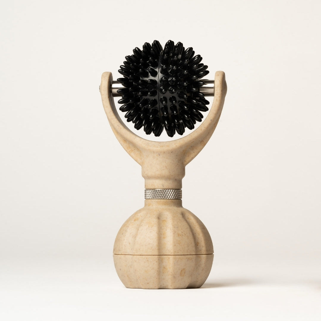 A handheld massage roller with a textured beige round handle, a black spikey massage ball, set against a plain off-white background.