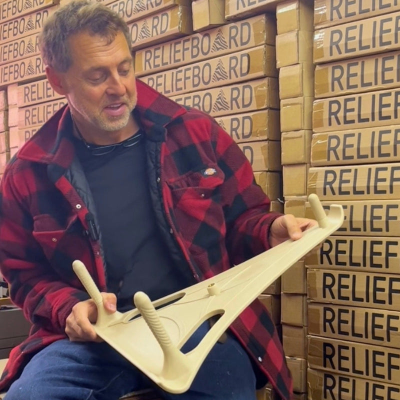 The inventor of the Reliefboard holding it while sat in front of a wall of stock.